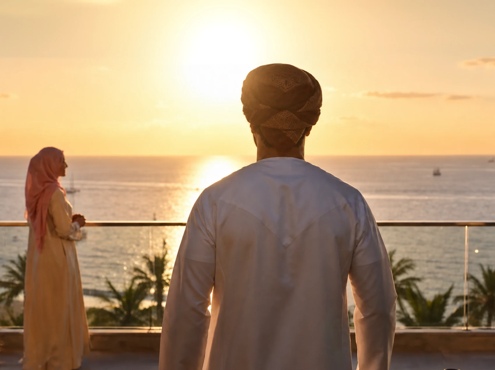 Omani residents overlooking the sea at sunset